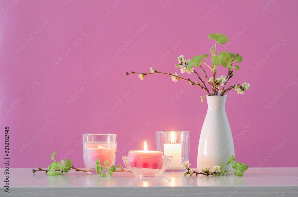 spring cherry flowers and candles on pink background