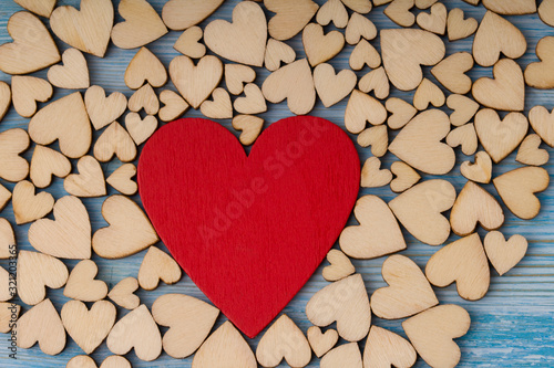 Many small wooden hearts and one big red heart  on blue background.