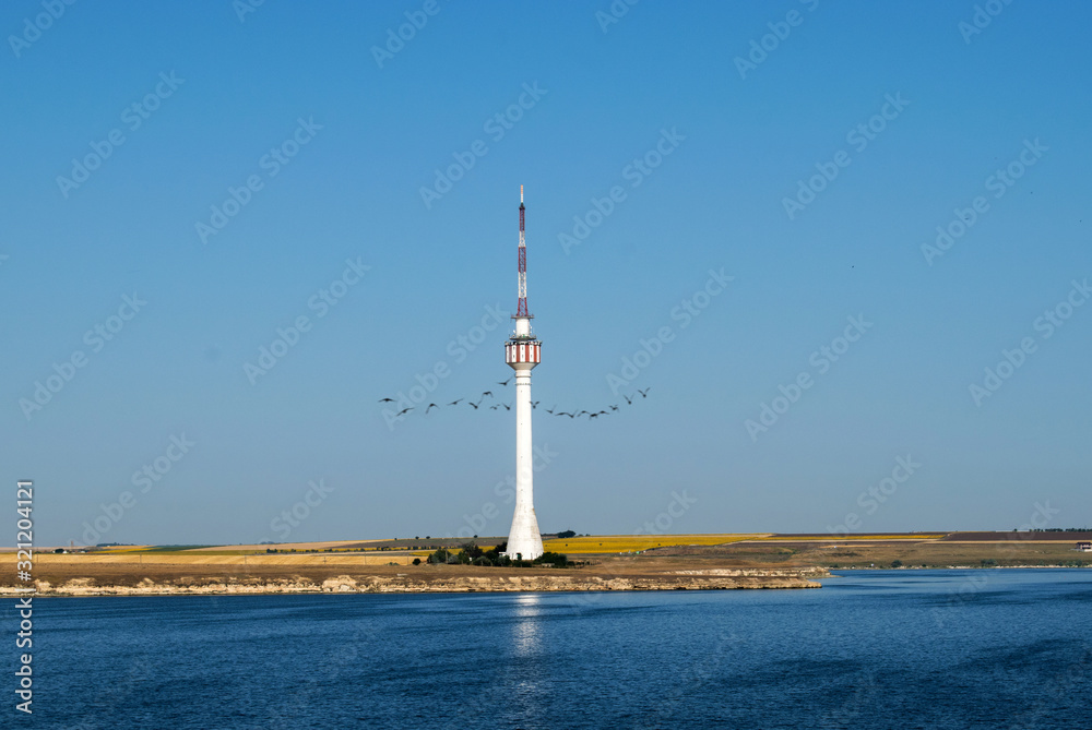 a high tower on the seashore. A beautiful blue sky and a sunflower chain in the distance a high tower on the seashore. A beautiful blue sky and a sunflower chain in the distance
