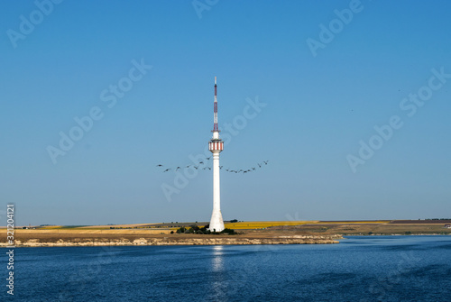 a high tower on the seashore. A beautiful blue sky and a sunflower chain in the distance © bogdan vacarciuc