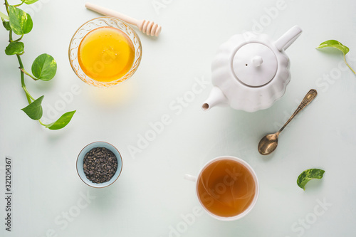 Fresh brewed tea, teapot and honey on a light table. White dishes. light background.