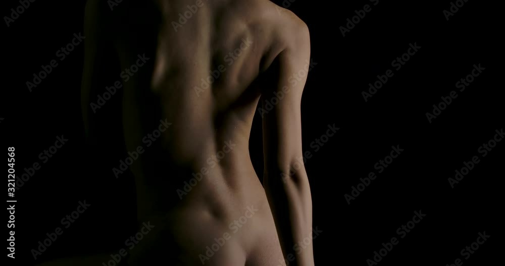 Close-up of Sexy young woman with naked lying and touching herself in low light on black background. Low key silhouette art nude.