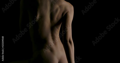 Close-up of Sexy young woman with naked lying and touching herself in low light on black background. Low key silhouette art nude.