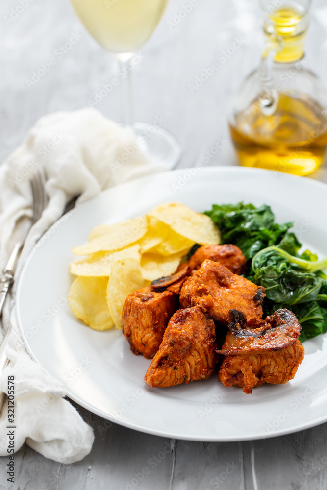 fried meat with potato chips and greens on white plate on ceramic background fried meat with potato chips and greens on white plate on ceramic background
