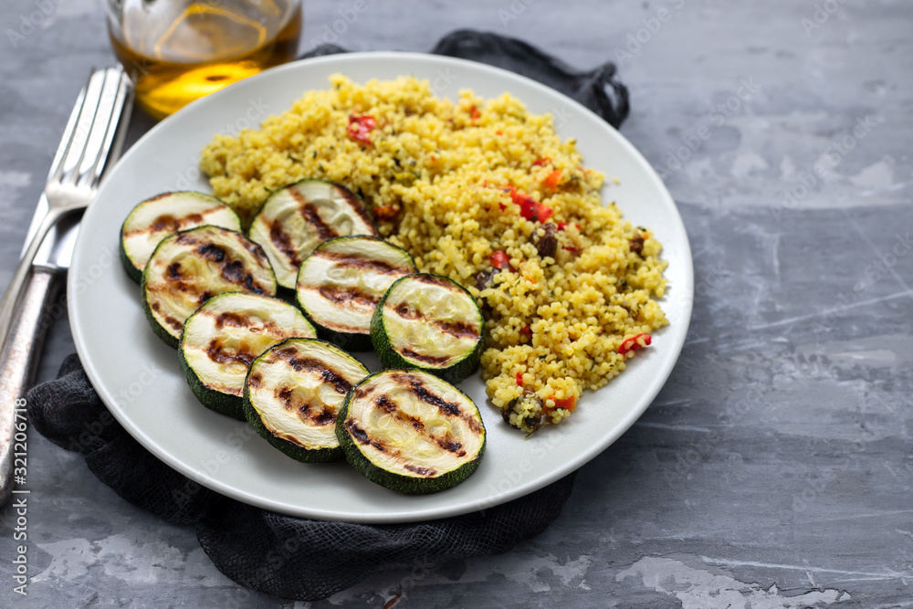 tabbouleh and grilled courgette on white plate on ceramic background