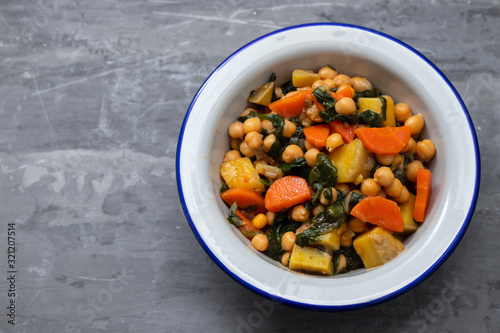 chick-pea with carrot and spinach on white bowl on ceramic background