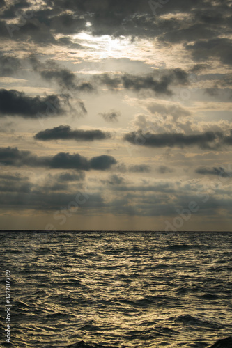 sunrise at sea  with a dramatic sky full of black clouds. A stormy summer day