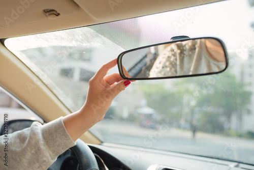 Woman hands adjusting rear view mirror in the car