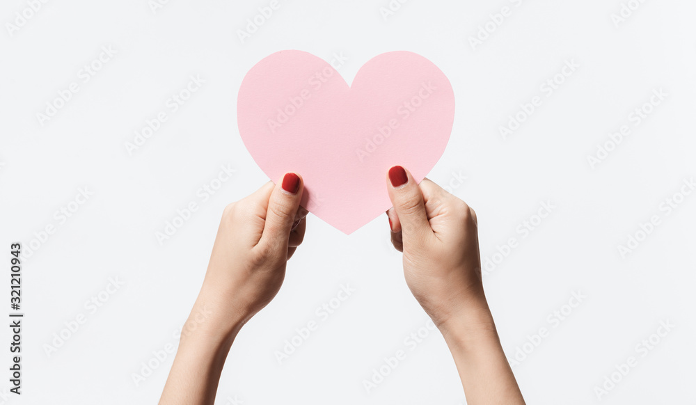 Close up women holding pink blank  paper with heart shape on white background.