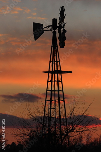 windmill at sunset with a colorful sky out in the country north of Hutchinson Kansas USA.