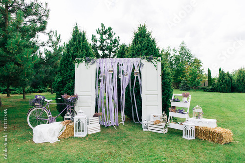 Stylish decorated wedding arch with doors and bycicle, hey and lavander. 