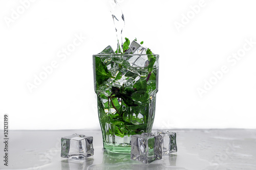 ice and mint fall in a cocktail spray. Rum with mint and ice in a glass.