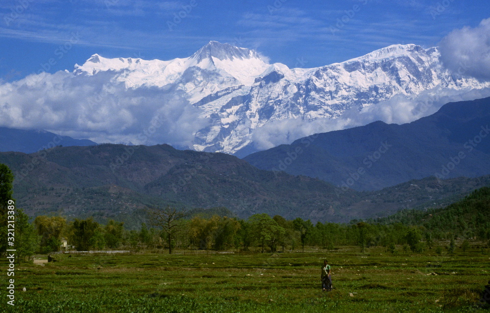 A Nepali women working in the field with a back-drop of Annapurna Range, near Pokhara, Nepal.