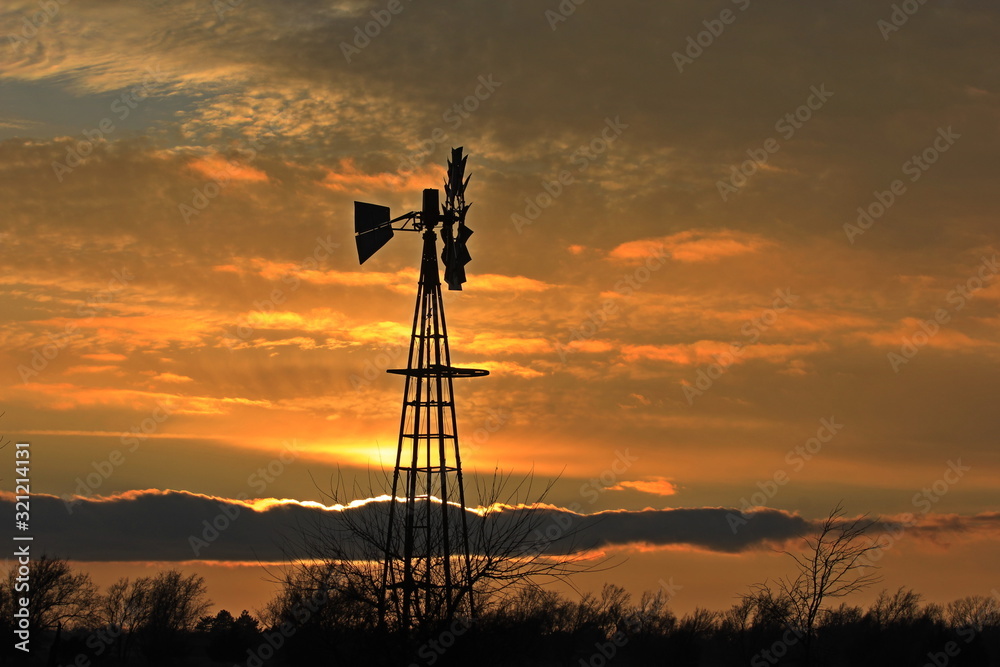 sunset over field with clouds and a Windmill silhouette.