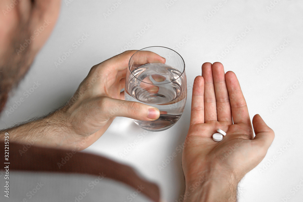Fototapeta premium A man holds in his hand a portion of pills for treatment.