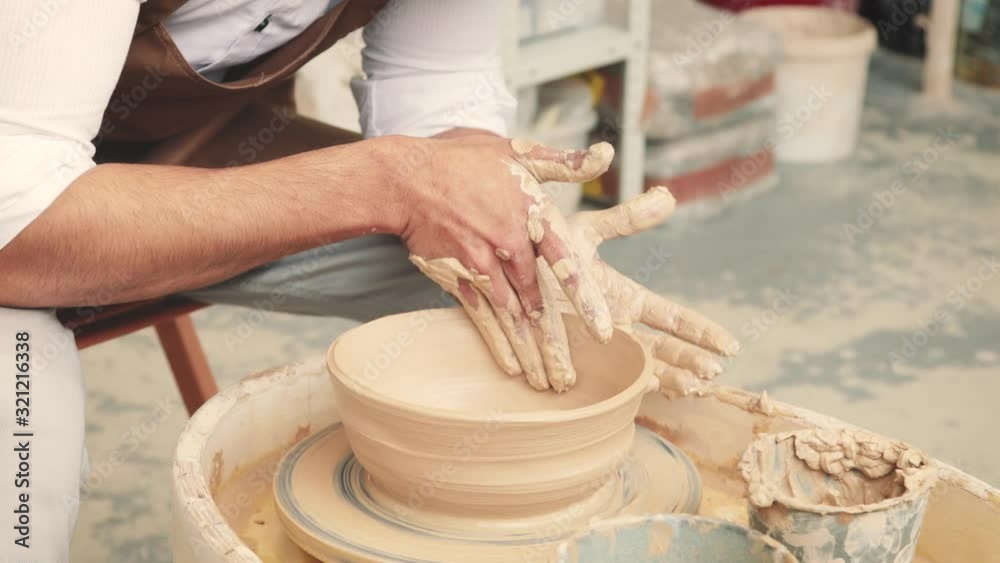 Creating vase of beige clay close-up. The sculptor in workshop makes jug out of clay closeup. Twisted potter's wheel. Master crock. Potter's work close-up. Man hands making clay jug. Handmade Creating vase of beige clay close-up. The sculptor in workshop makes jug out of clay closeup. Twisted potter's wheel. Master crock. Potter's work close-up. Man hands making clay jug. Handmade