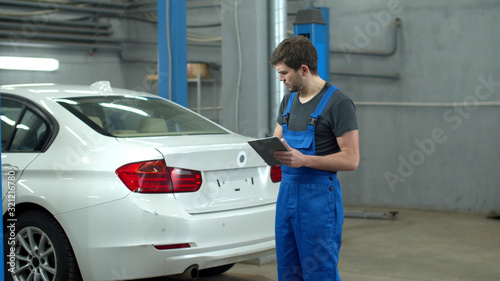 Mechanic with a tablet inspects a car 