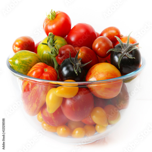 Bunte, exotische, historische Tomaten Vielfalt, von schwarz bis gestreift, süß und saftig in einer Schale vor weißem Hintergrund presentiert.