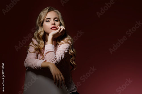 Portrait of stylish fashionable blonde woman in pink shirt posing on dark pink background. copy space