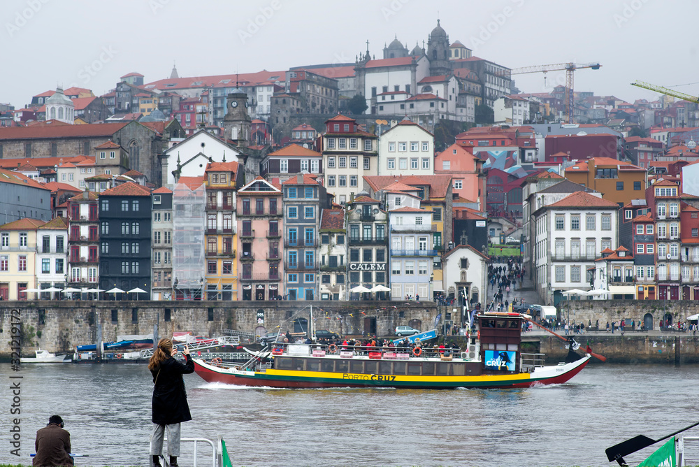 Fototapeta premium December 8, 2019 Porto, Portugal. Woman photographing with the mobile the port of Porto and its colorful houses
