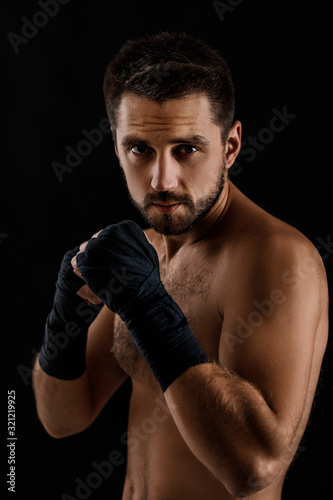 Muscular boxing man ready to fight on black background