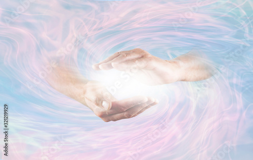 Working with Powerful Divine Energy - male hands emerging from blue pink rotating energy field background with bright white light energy between hands