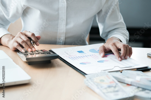 Businesswoman analyzing investment charts and pressing calculator buttons over documents. Accounting Concept.
