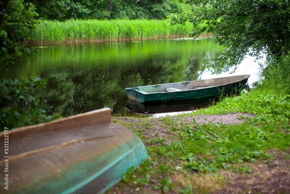 Boat on the Bank of a calm river, reflections of green trees Boat on the Bank of a calm river, reflections of green trees