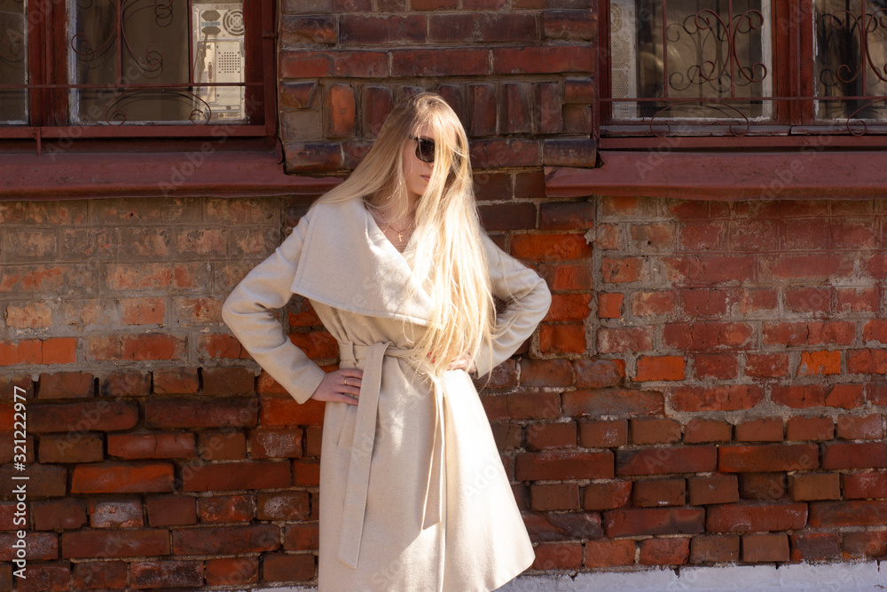Naklejka premium Street portrait of a blonde with long hair, in a light beige raincoat