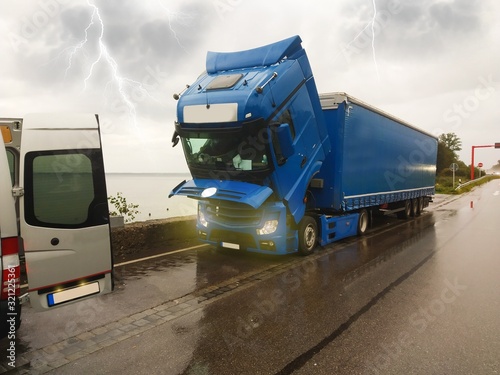 A broken truck, with the cab lowered, is waiting for a repair car service.It`s a storm and lightning.Broken truck, mobile car service, highway and storm. Traffic complications. photo