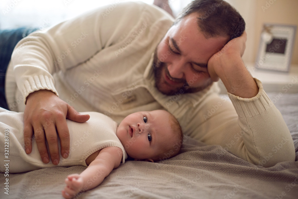 big father with a beard is lying with his child on the bed big father with a beard is lying with his child on the bed