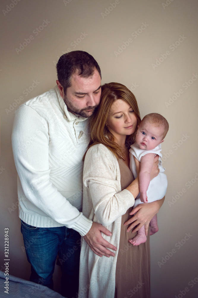 mom and dad are standing with the child at the wall of the house