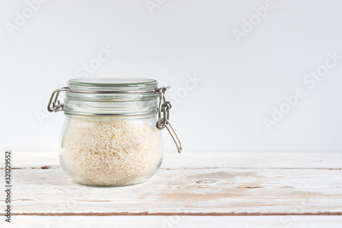 White rice in a glass jar on a wooden table on a light background. Cooking food. Close-up. The concept of vegetarianism and a balanced diet.