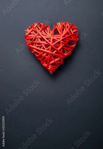 Red wicker heart made of twigs on a black background with place for text
