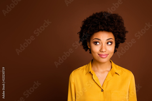 Closeup photo of beautiful pretty dark skin wavy lady positive good mood look side empty space interested have creative idea wear yellow shirt isolated brown color background