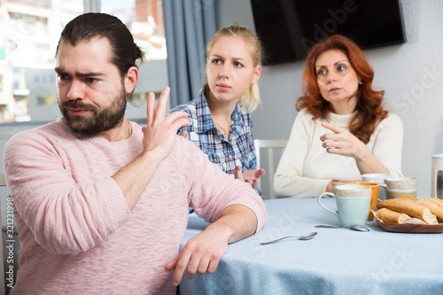 Angry wife and mother-in-law rebuking young man