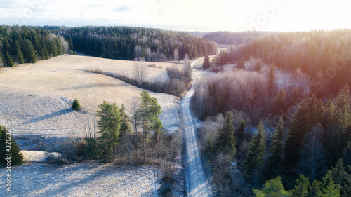 Aerial panorama of cold winter road in Sipoo National park in Finland, Europe. Picturesque cold winter panorama with snow on fields and meadows lit by winter sun. photo