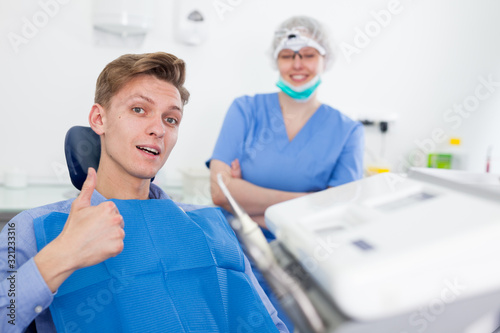 Portrait of satisfied man visiting dentist giving thumbs up in the dental clinic