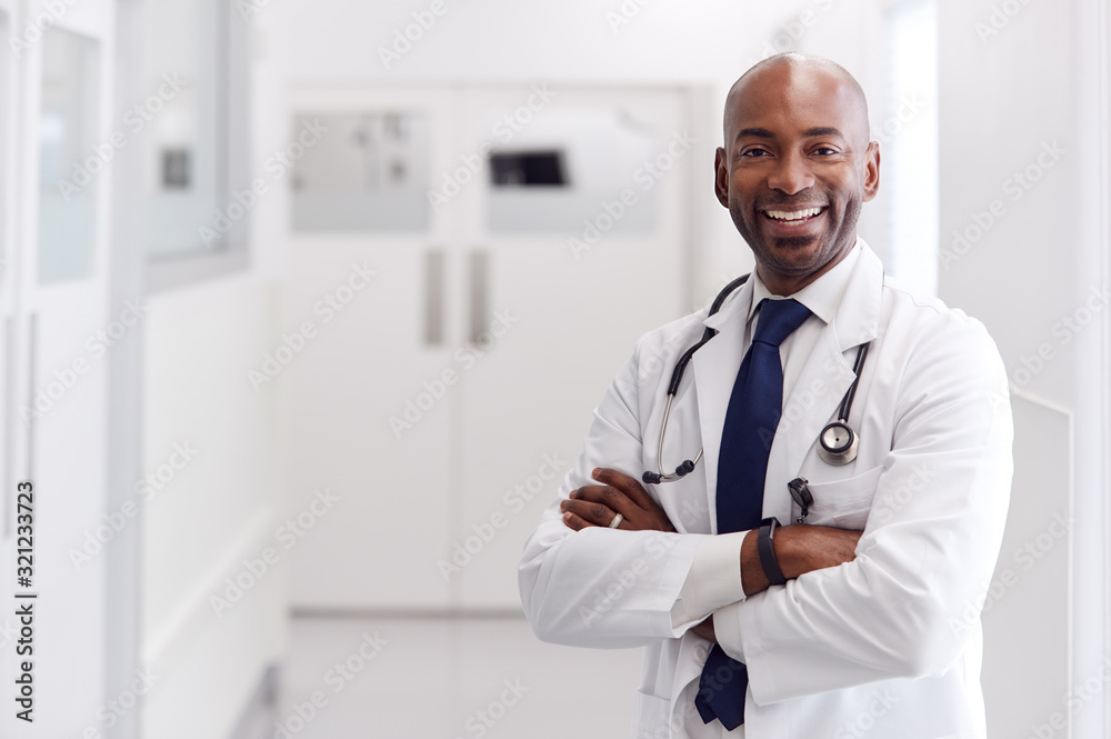 Portrait Of Mature Male Doctor Wearing White Coat Standing In Hospital Corridor Portrait Of Mature Male Doctor Wearing White Coat Standing In Hospital Corridor