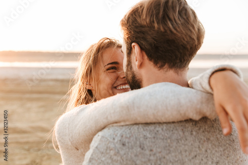 Beautiful young couple standing at the sunny beach