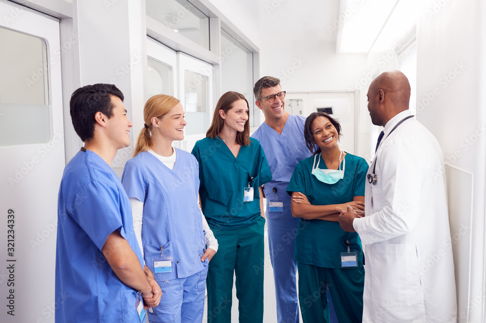 Multi-Cultural Medical Team Having Meeting In Hospital Corridor Multi-Cultural Medical Team Having Meeting In Hospital Corridor