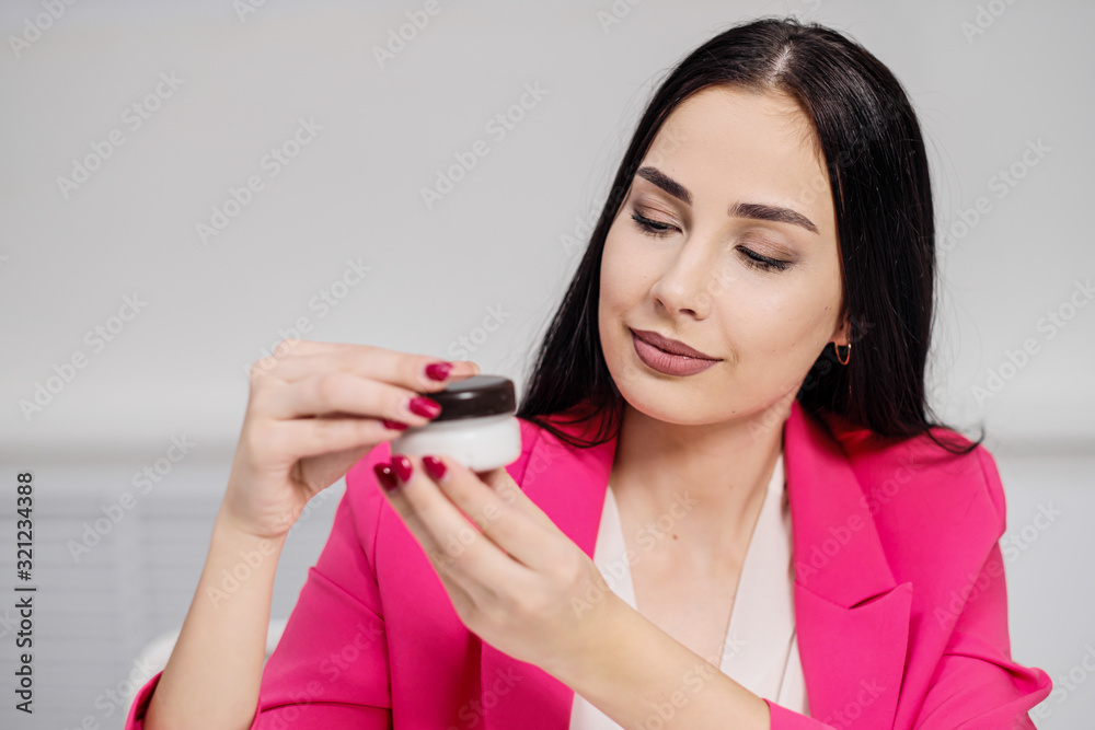 A beautiful young woman blogger in a pink jacket shoots a blog about cosmetics. A beautiful young woman blogger in a pink jacket shoots a blog about cosmetics.