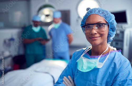 Portrait Of Female Surgeon Wearing Scrubs And Protective Glasses In Hospital Operating Theater photo