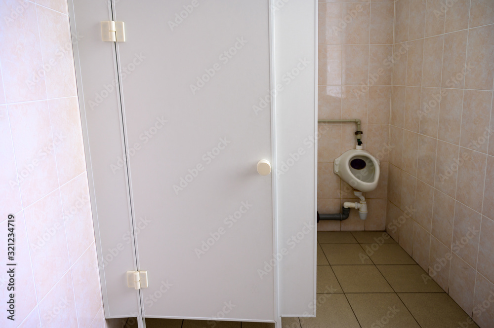 Photo of a toilet in a toilet with a window and a door in a building Photo of a toilet in a toilet with a window and a door in a building