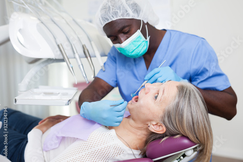 Dentist is treating female patient which is sitting in dental chair in clinic