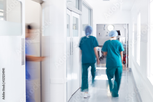 Motion Blur Shot Of Medical Staff Wearing Scrubs In Busy Hospital Corridor photo