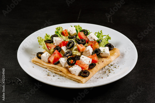 Slika na platnu Thin pancakes with vegetables on black background