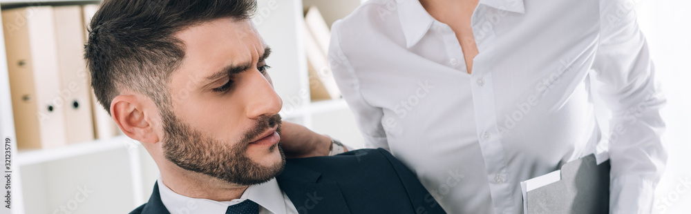 Obraz premium panoramic shot of secretary with big breast touching shocked businessman in office