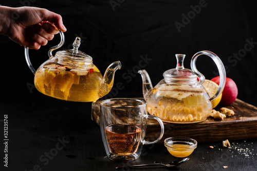 Glass teapots with fruit tea in composition on black background
