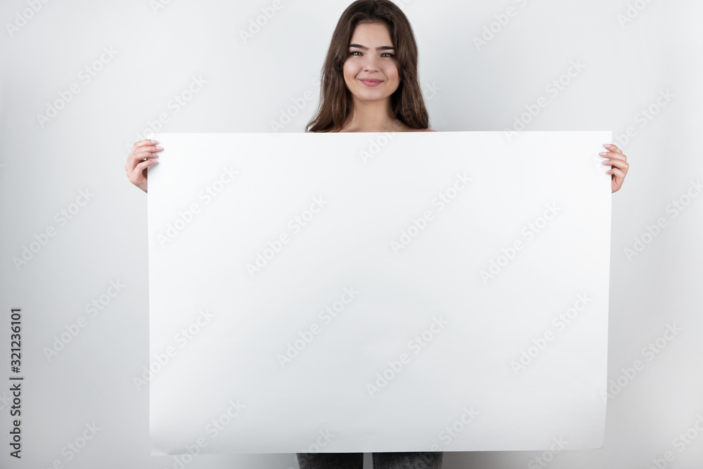 young beautiful woman shows a white sheet of paper in the camera on a empty background. Mockup Copy Paste on isolated white background young beautiful woman shows a white sheet of paper in the camera on a empty background. Mockup Copy Paste on isolated white background
